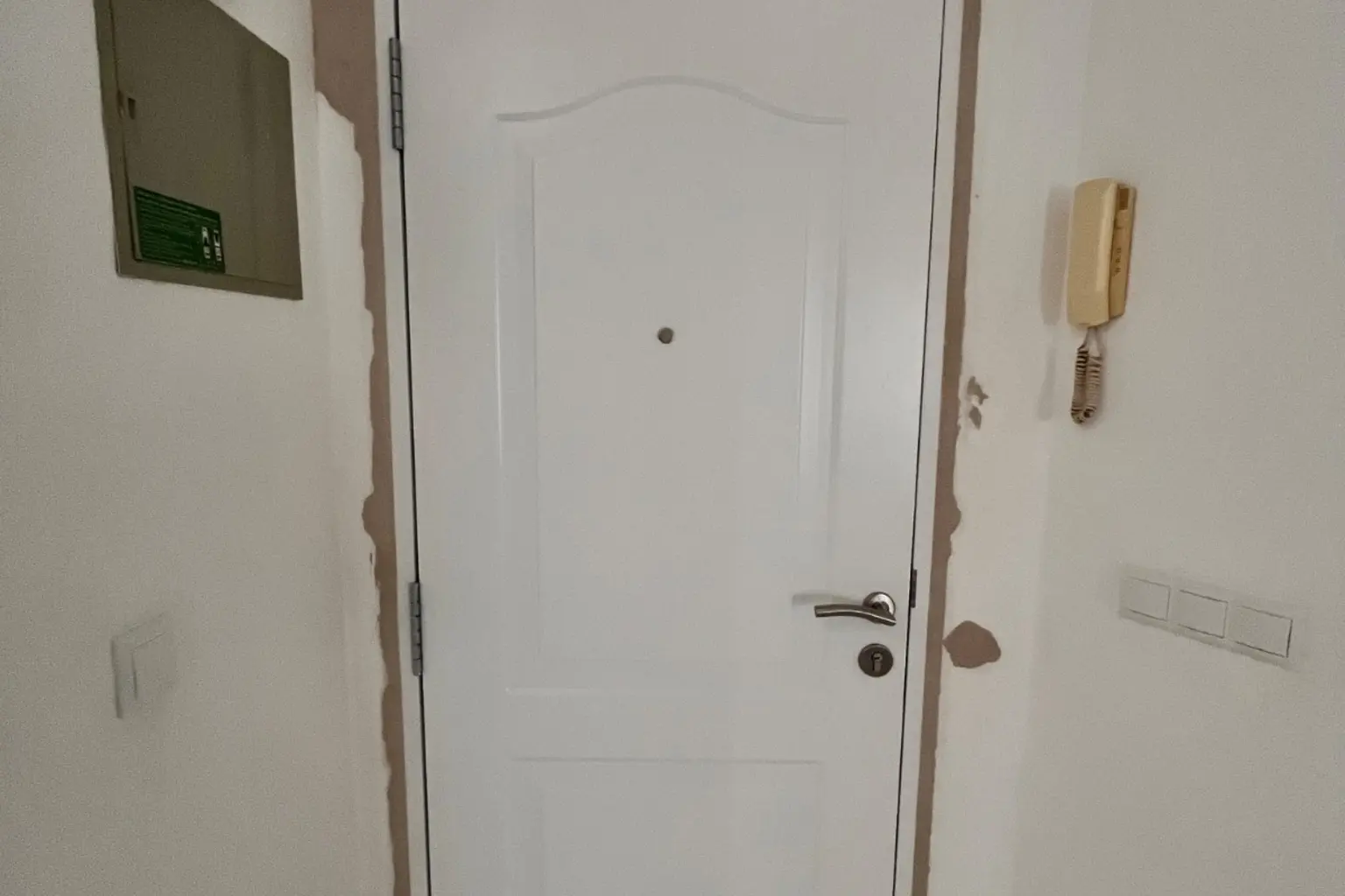 Puerta de entrada blanca recién instalada, con el cerco todavía por rematar