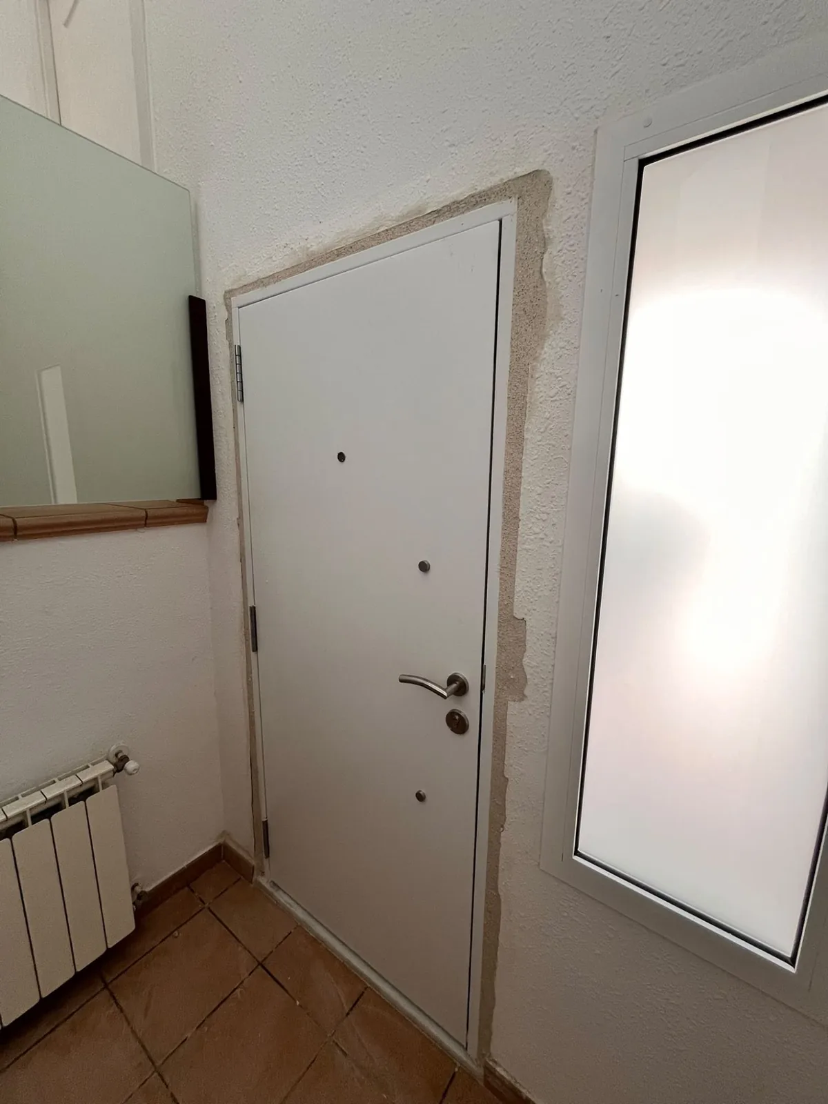 White armoured door just fitted, with the reveal still to be made good