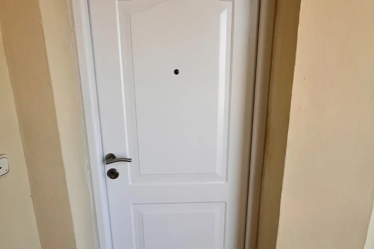 Puerta de entrada blanca panelada en el rellano de una vivienda
