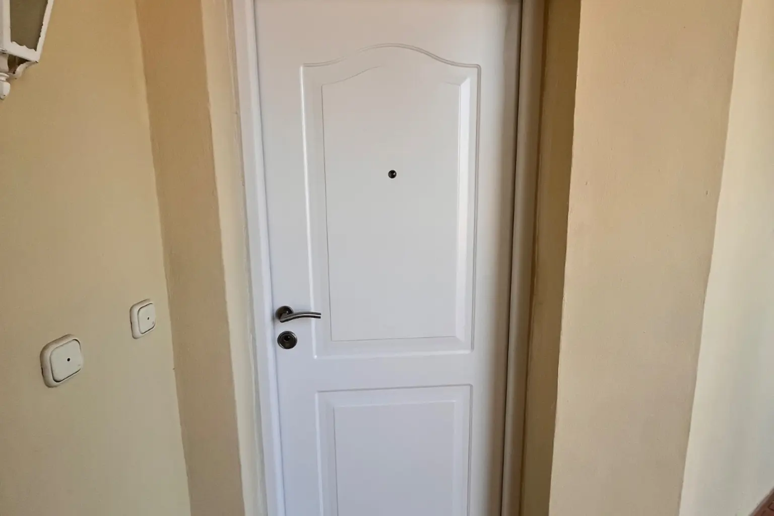 Puerta de entrada blanca panelada con el herraje ya montado