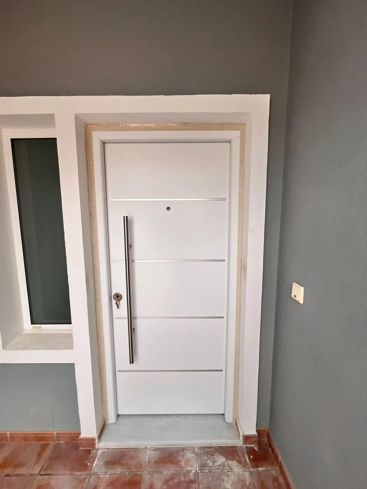 White front door with a stainless steel bar handle, fitted and finished