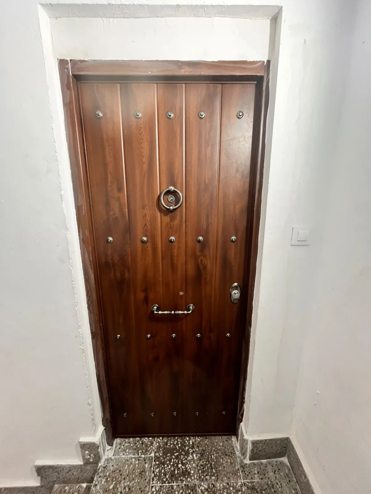 Wooden armoured front door with studs and a ring knocker, seen head-on